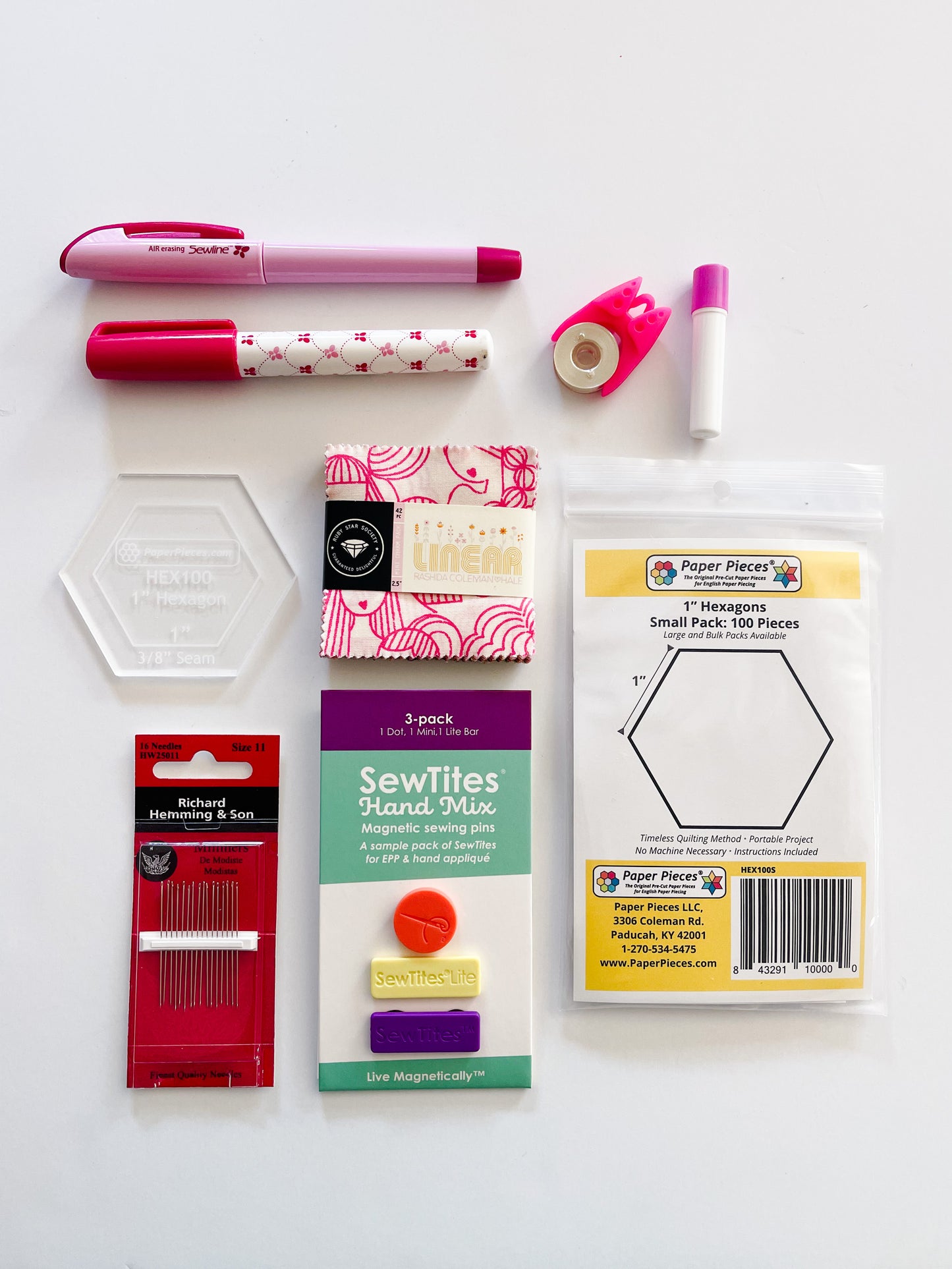 Essential supplies for English Paper Piecing including paper hexagons, hexagon template, sewline glue pen, milliners needles, sewtites magnetic pins, and an air erasable pen for tracing your fussy cuts. The EPP kit also includes a mini charm pack.